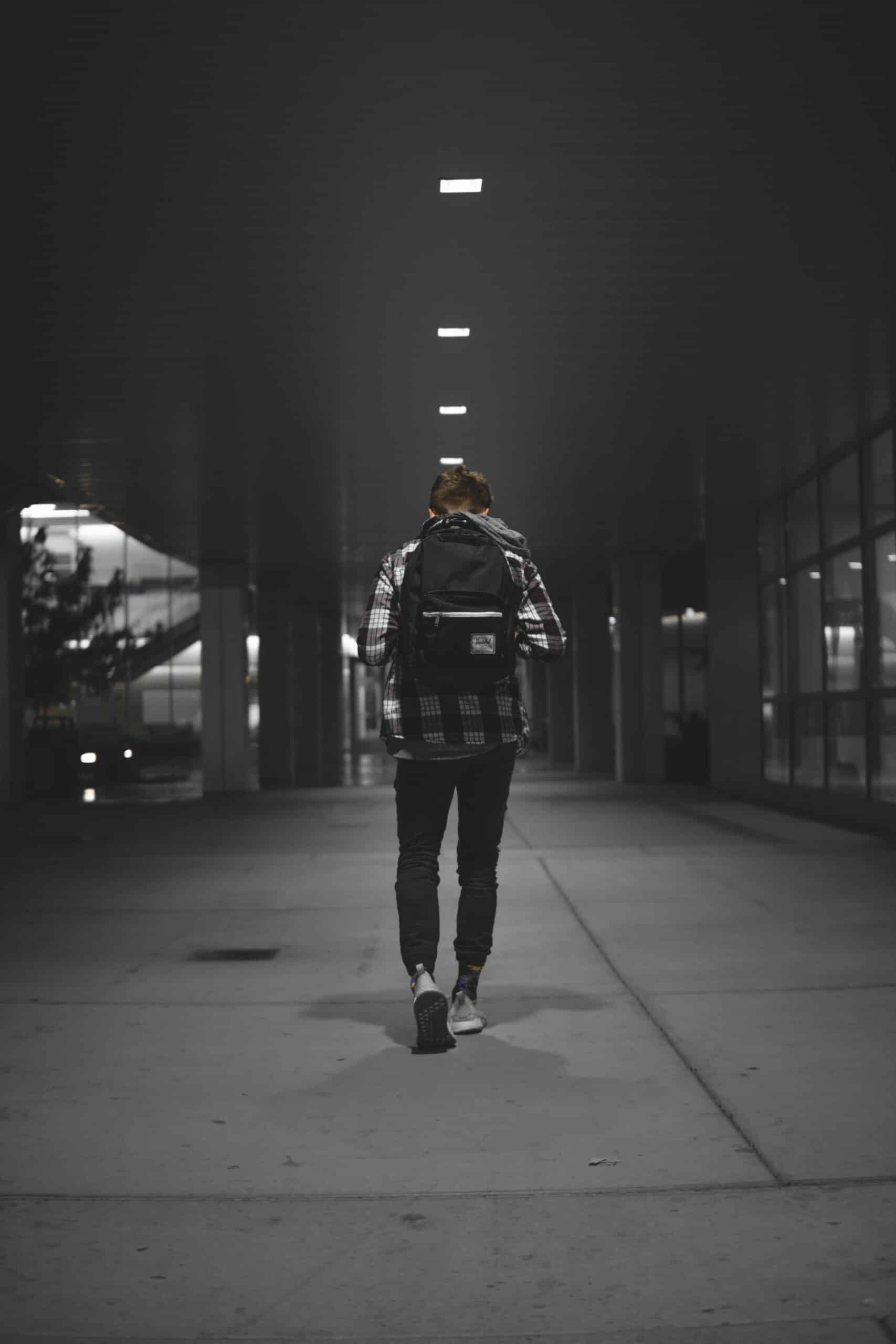 man with backpack walking alone on pathway